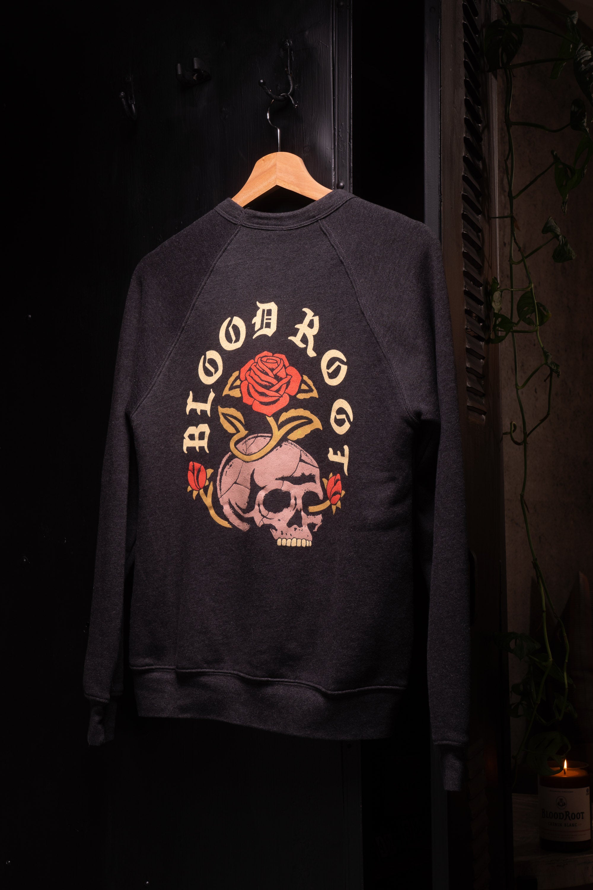 Skull and roses design with BloodRoot name on the back of a dark gray crew neck sweatshirt