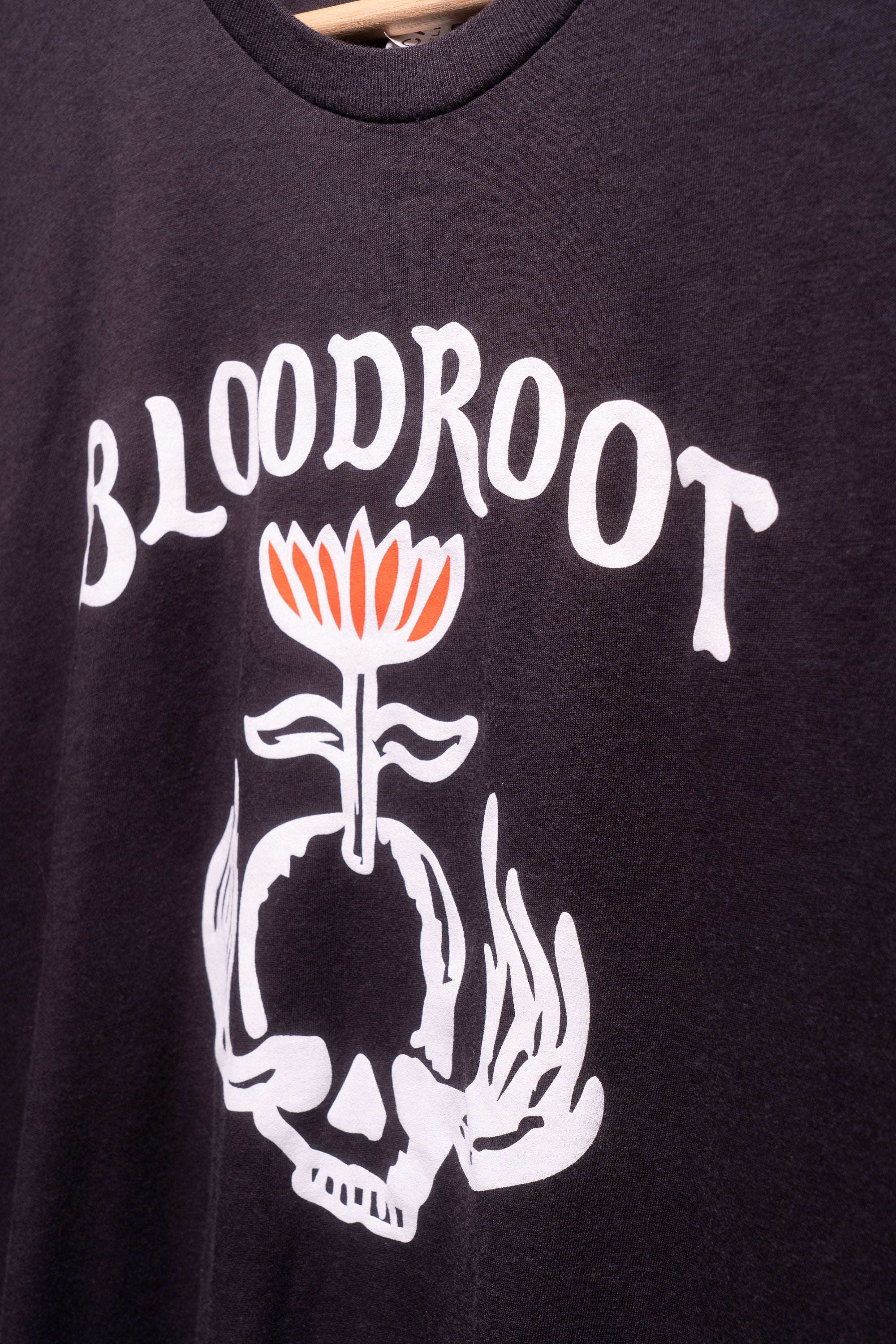 Zoomed in view of white BloodRoot logo on black t-shirt