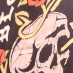 Close up view of skull with roses surrounding featured on the back of black hoodie