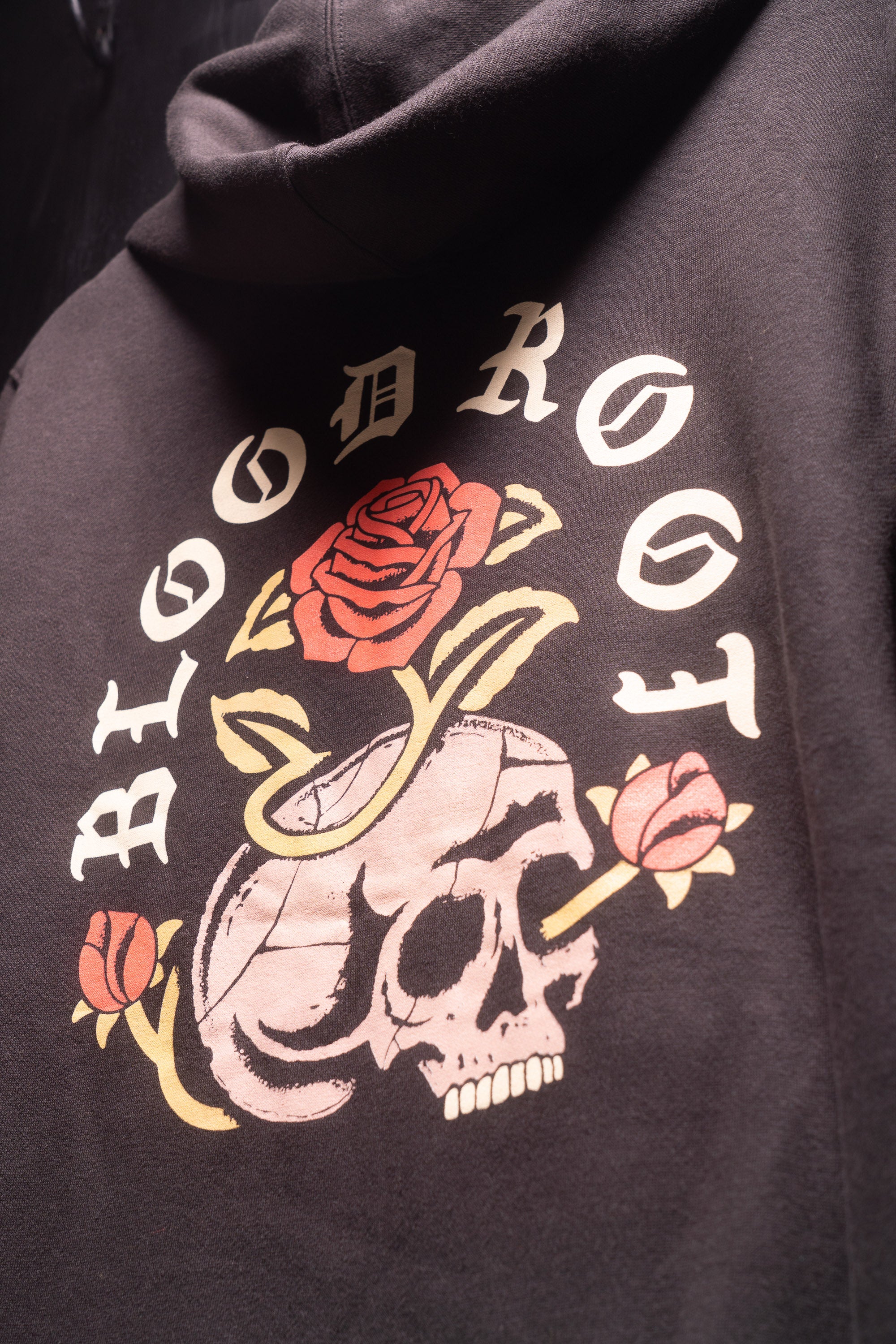 Close up view of BloodRoot Skull and Roses design on the back of black hoodie