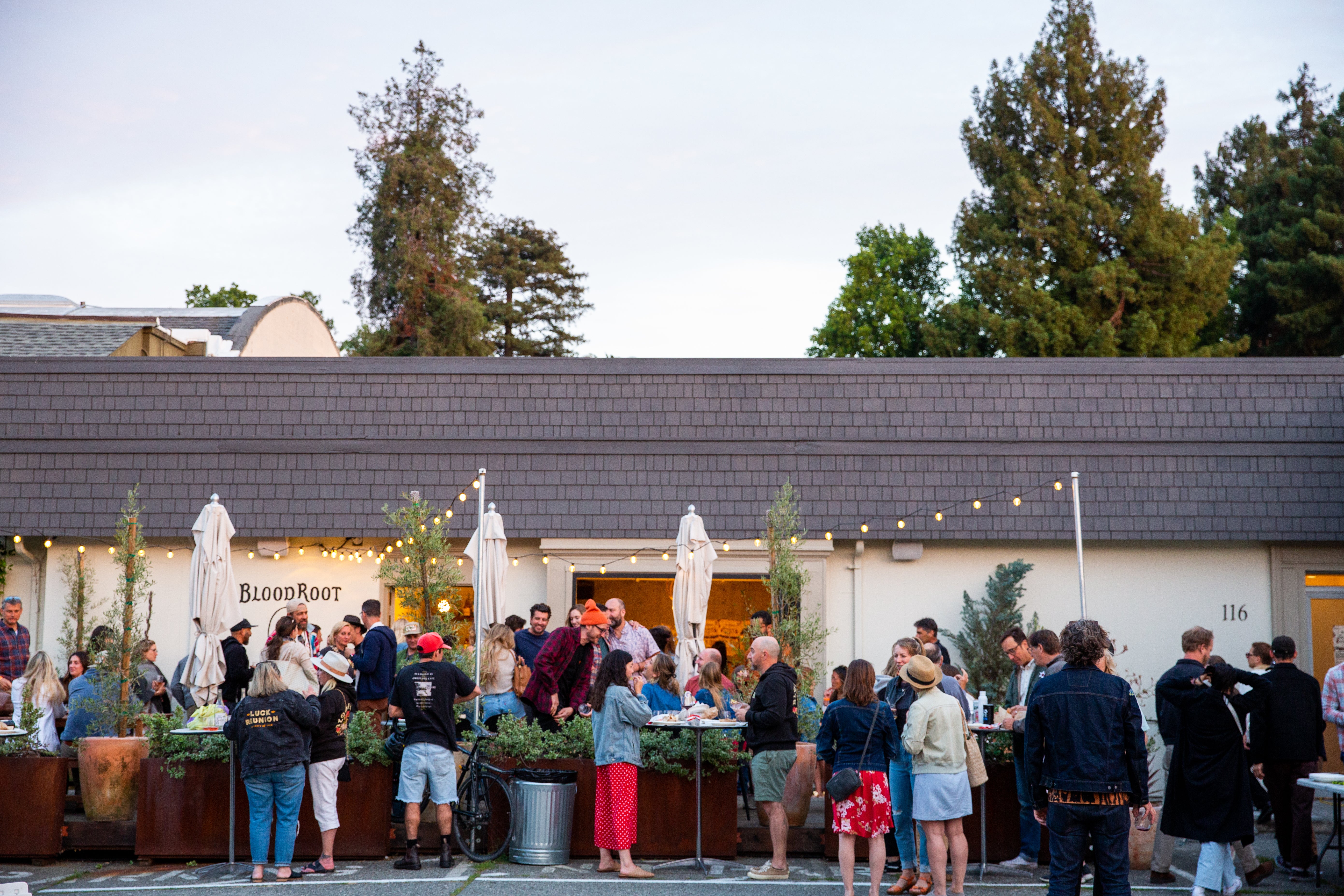 A crowd is gathered enjoying drinks and food outside of the BloodRoot tasting room.