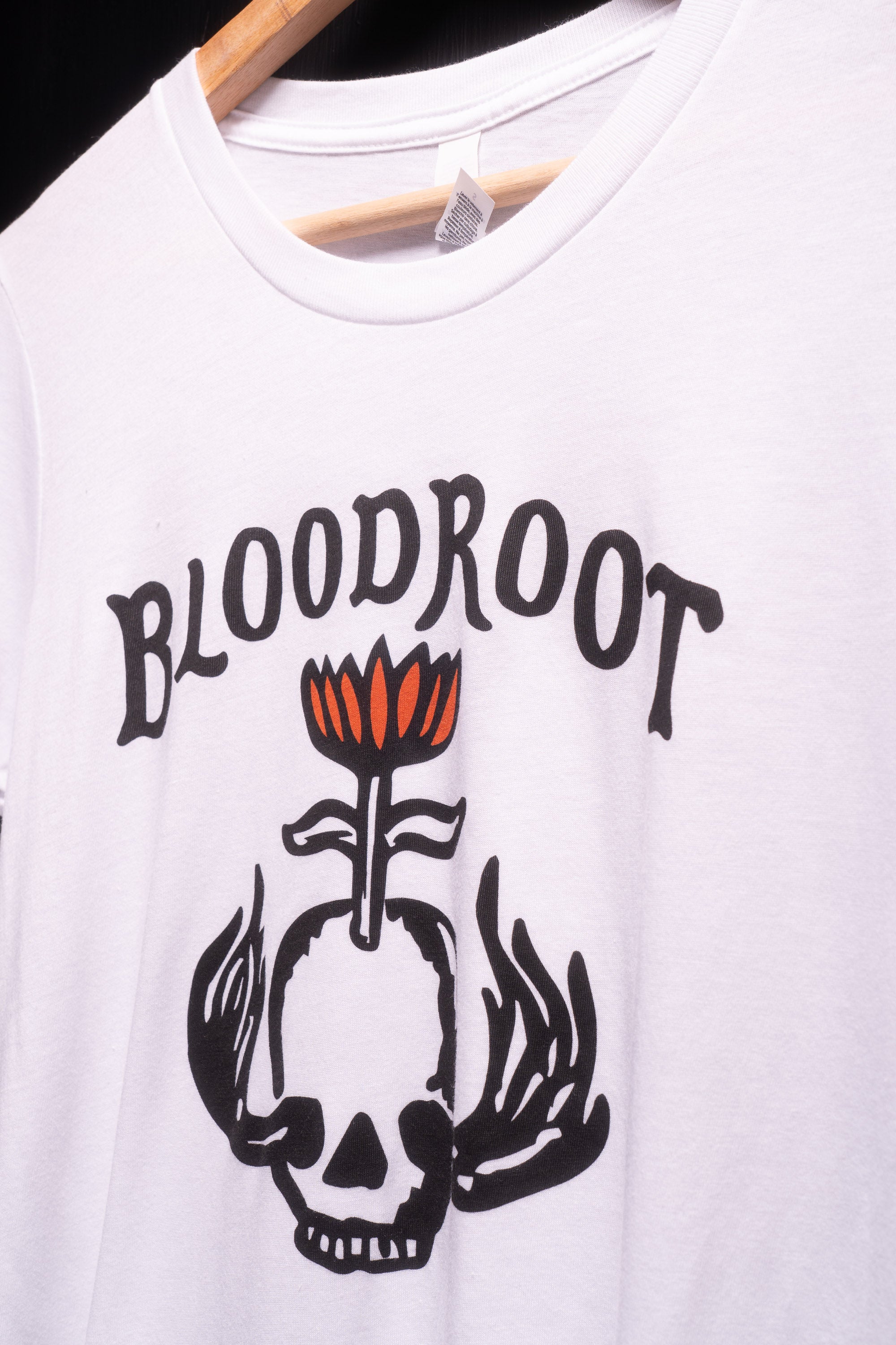 Zoomed in view of black BloodRoot logo on white t-shirt