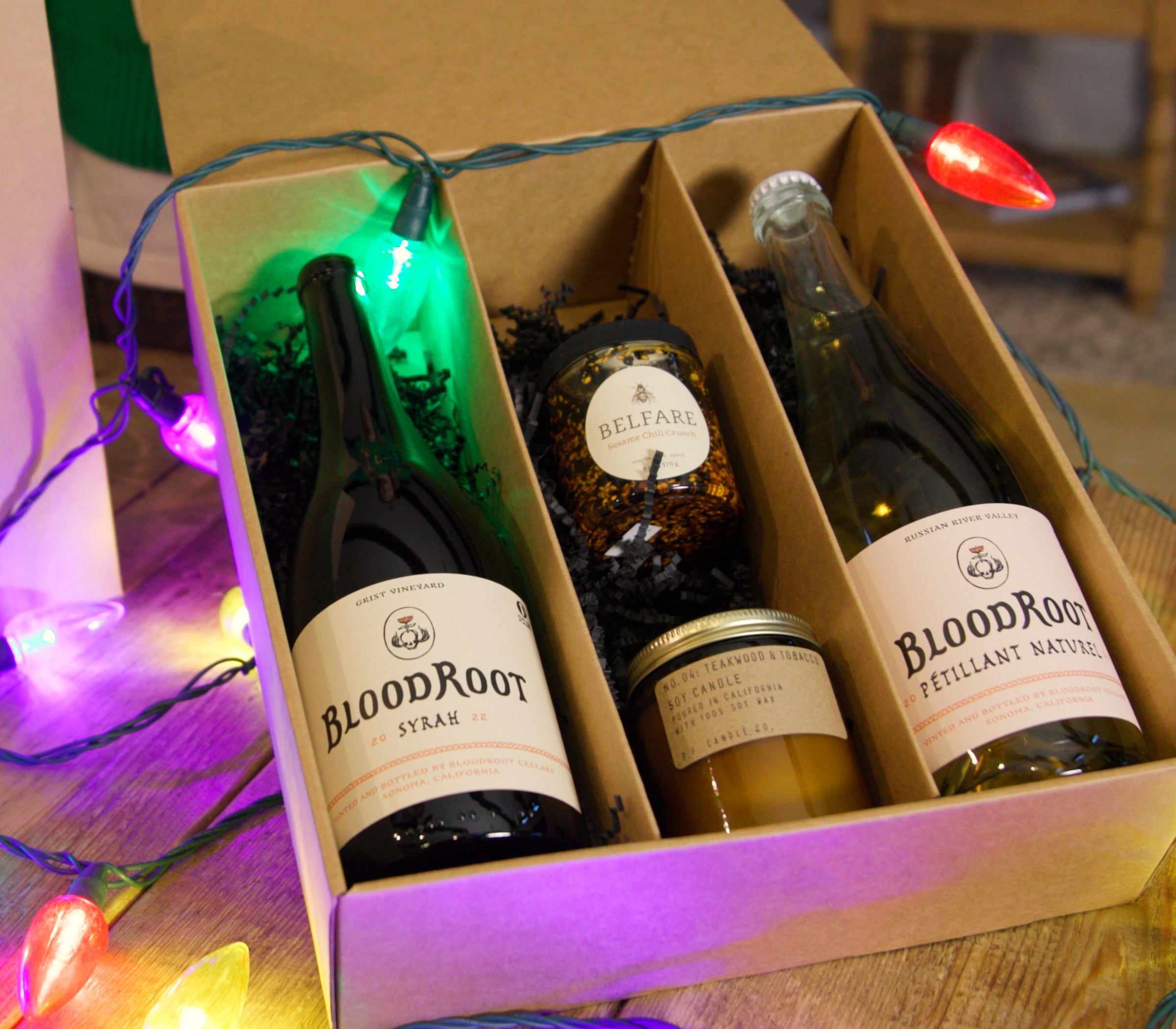 Two bottles of BloodRoot wine in a gift box with decorative lights around.